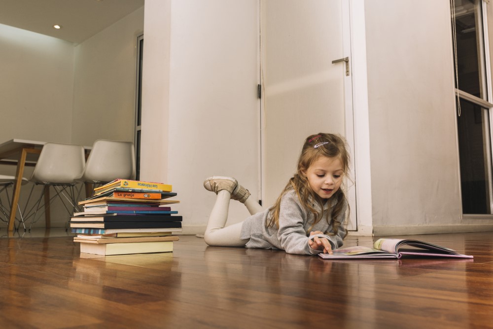 girl child studying on hardwood floor